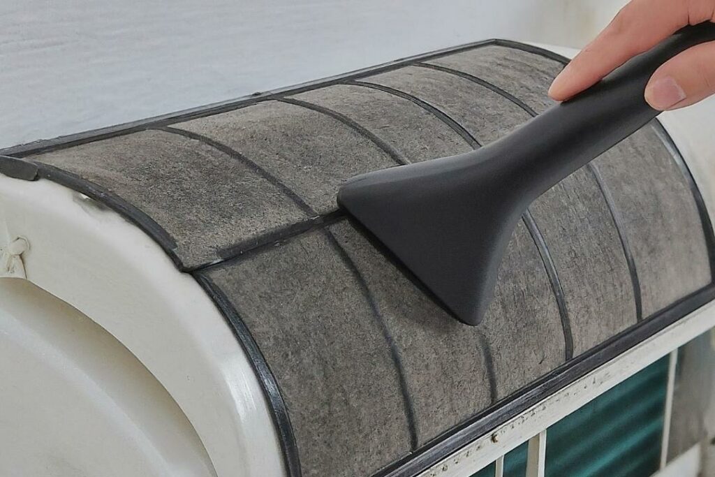 closeup of someone vacuuming an aircon filter